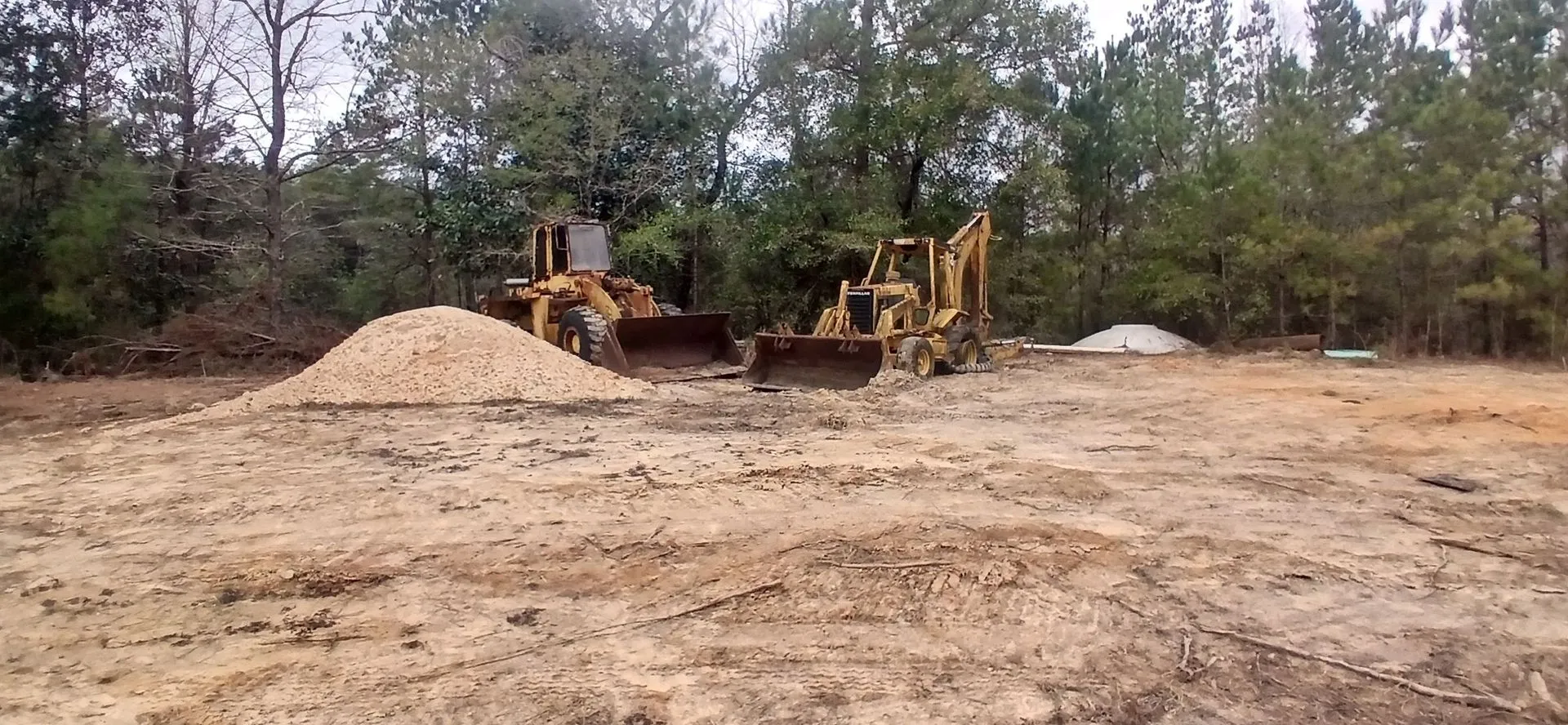 Wheel loader and backhoe beside a stockpile