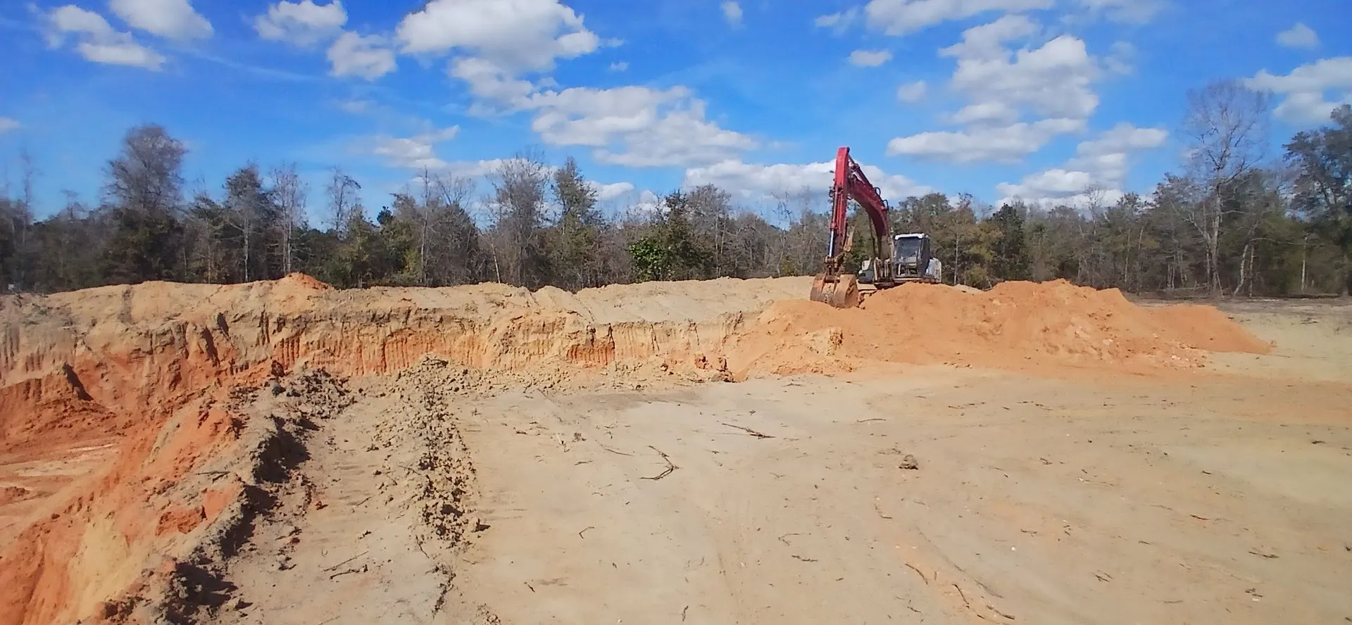 Excavator on the ridge above the sand floor